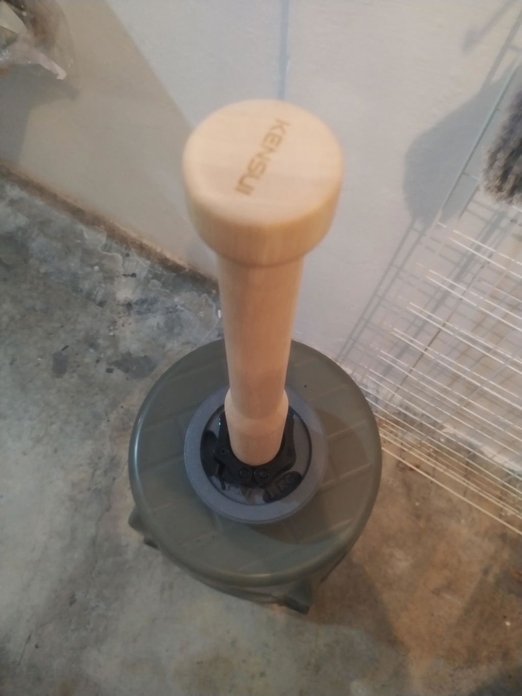 Wooden training club standing in a weight plate base