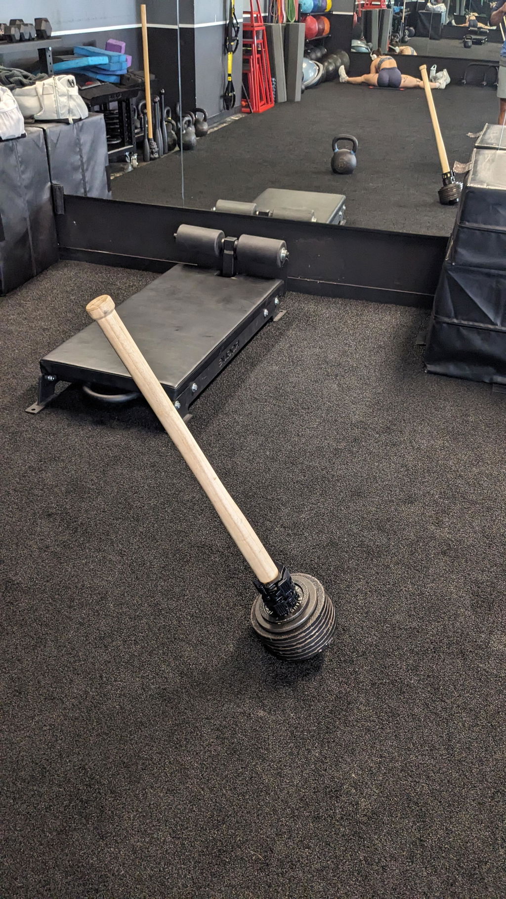 Steel mace lying on a gym floor with the weighted head loaded