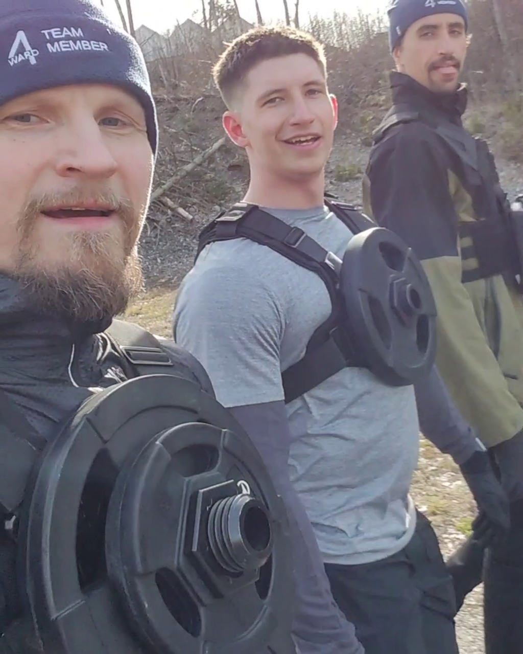 Three lifters outdoors wearing plate-loaded weight vests