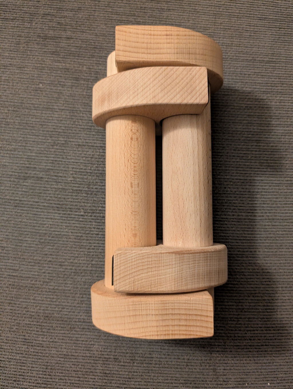 Two wooden parallettes snapped together into one block on a carpet