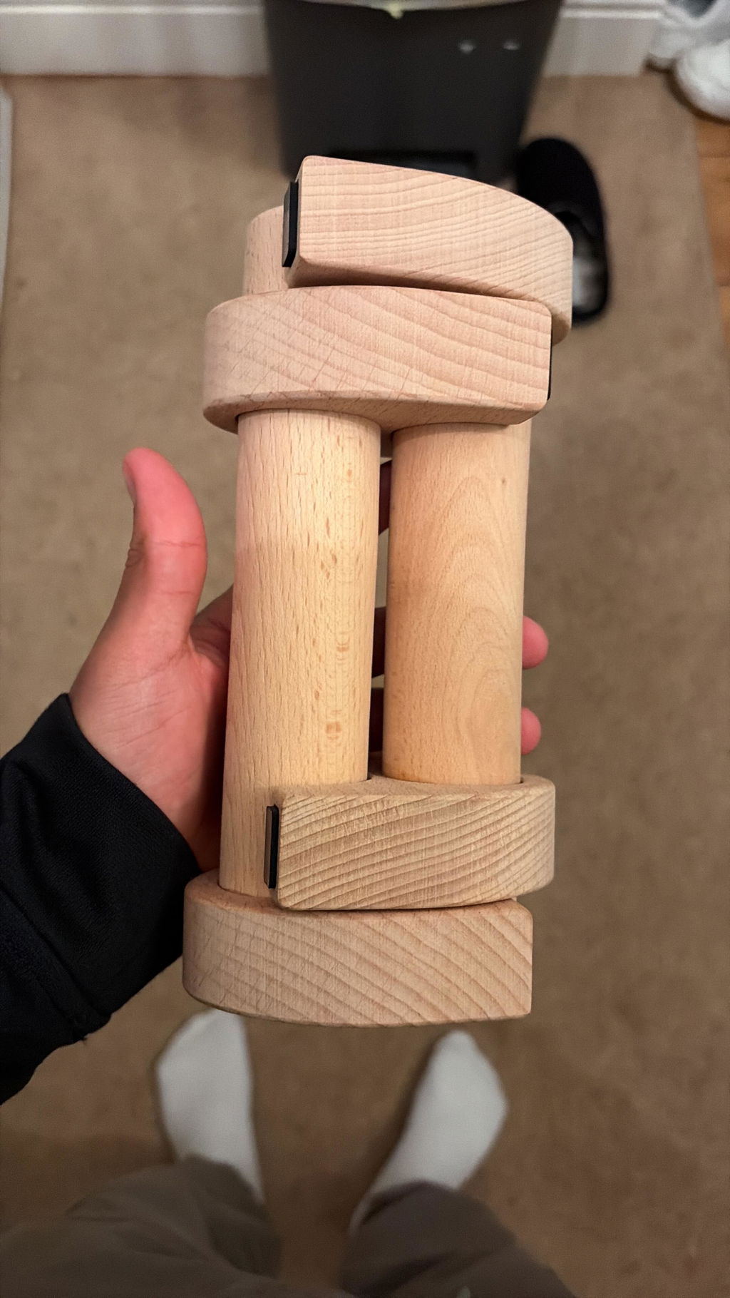A hand holding a pair of wooden parallettes snapped together into one block