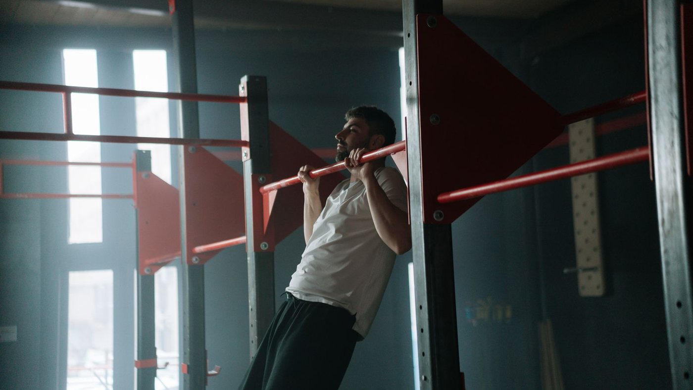 A man pulling his chin over a bar in a dimly lit gym